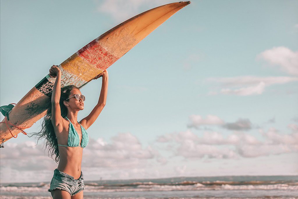 Best Resorts for Solo Female Travelers - woman wih a surf board