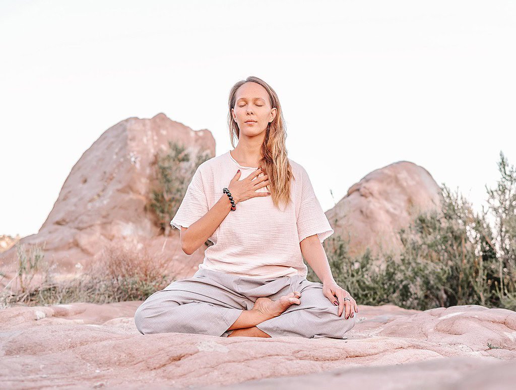 best solo yoga retreas - woman doing yoga and meditating in a desert