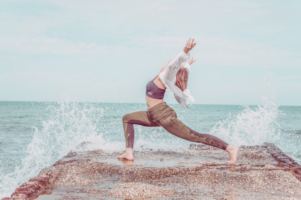 woman doing yoga by the ocean